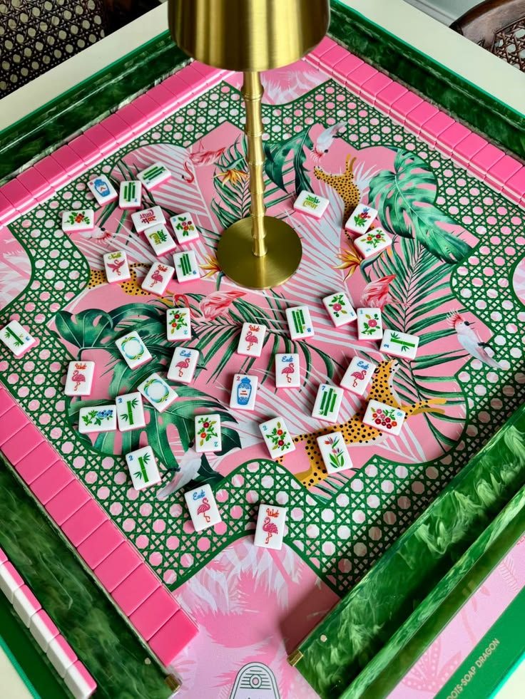 A pink and green tropical mahjong table set with a brass lamp